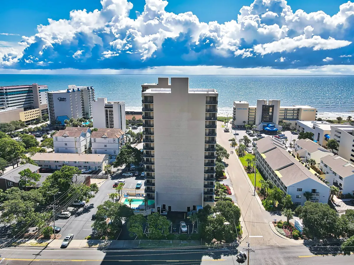 An inviting exterior perspective featuring the ocean, a pool, beach access, and the surrounding buildings and street. The scene highlights easy transitions between poolside relaxation, beach walks, and exploring the neighborhood.