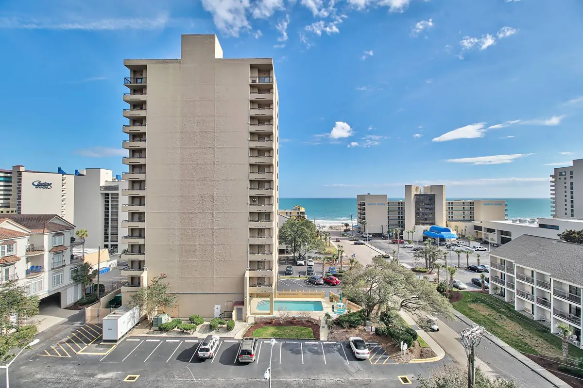 A panoramic look at the ocean and pool area, with surrounding residential buildings in view. The inviting scene highlights relaxation by the pool as well as the scenic coastline, spotlighting both leisure and exploration.
