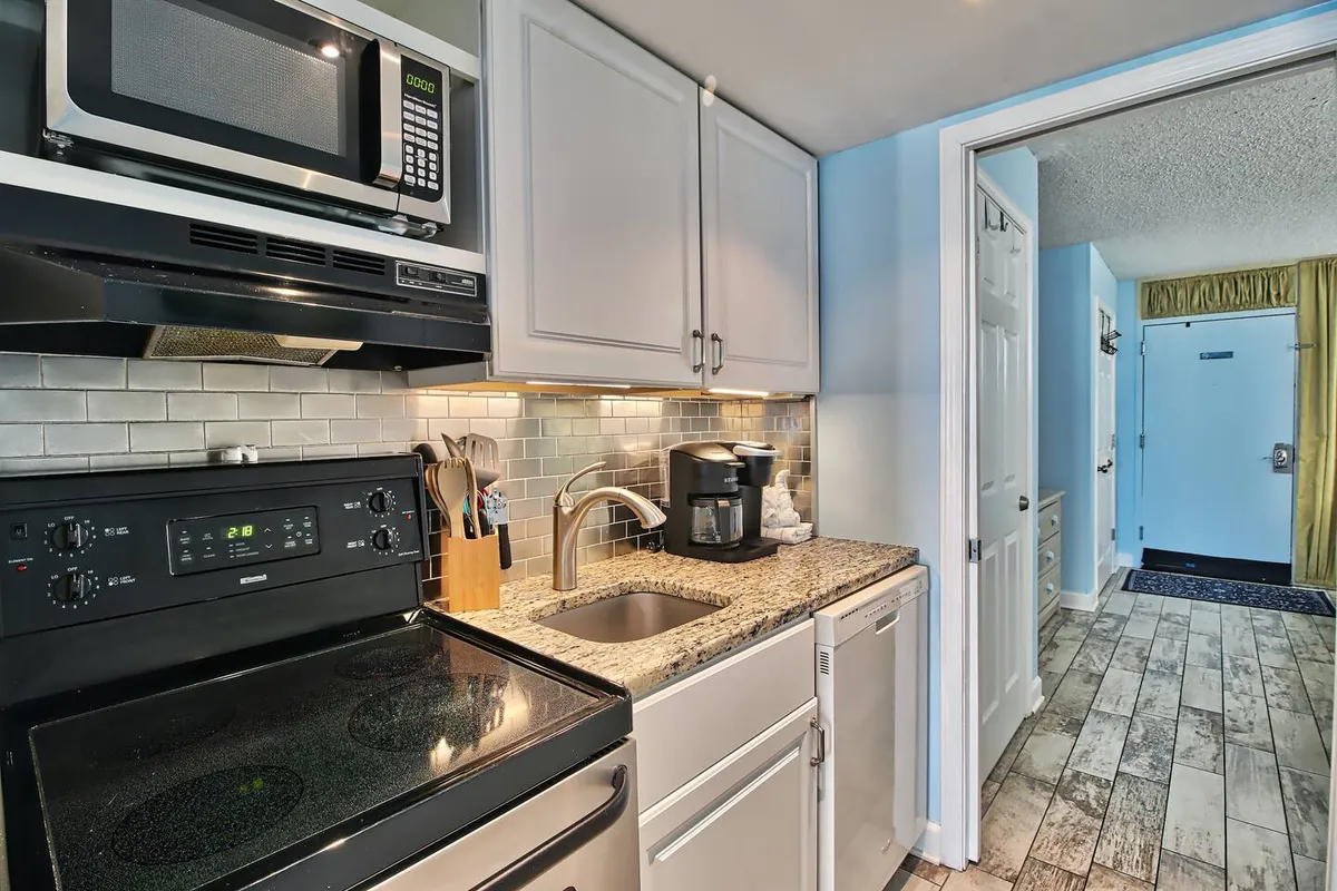 A bright, inviting kitchen featuring stainless steel appliances, a granite countertop, a well-placed kitchen sink, and a coffee maker. The layout showcases ample counter space and cabinetry, ideal for cooking, meal prep, and storing ingredients. The kitchen appears organized and functional, capturing the full suite of appliances mentioned in the section.